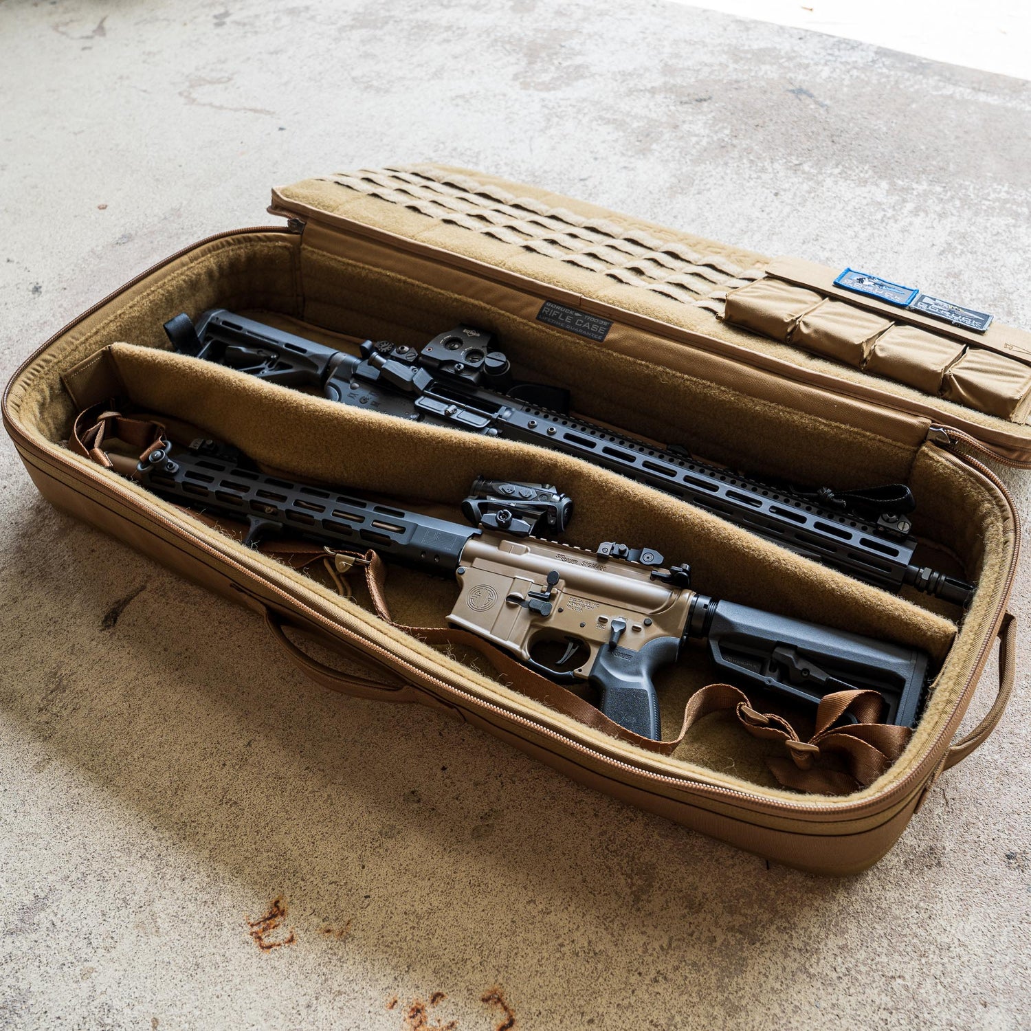 A tan Rifle Case with its lid open is displayed on a concrete floor, holding two rifles.