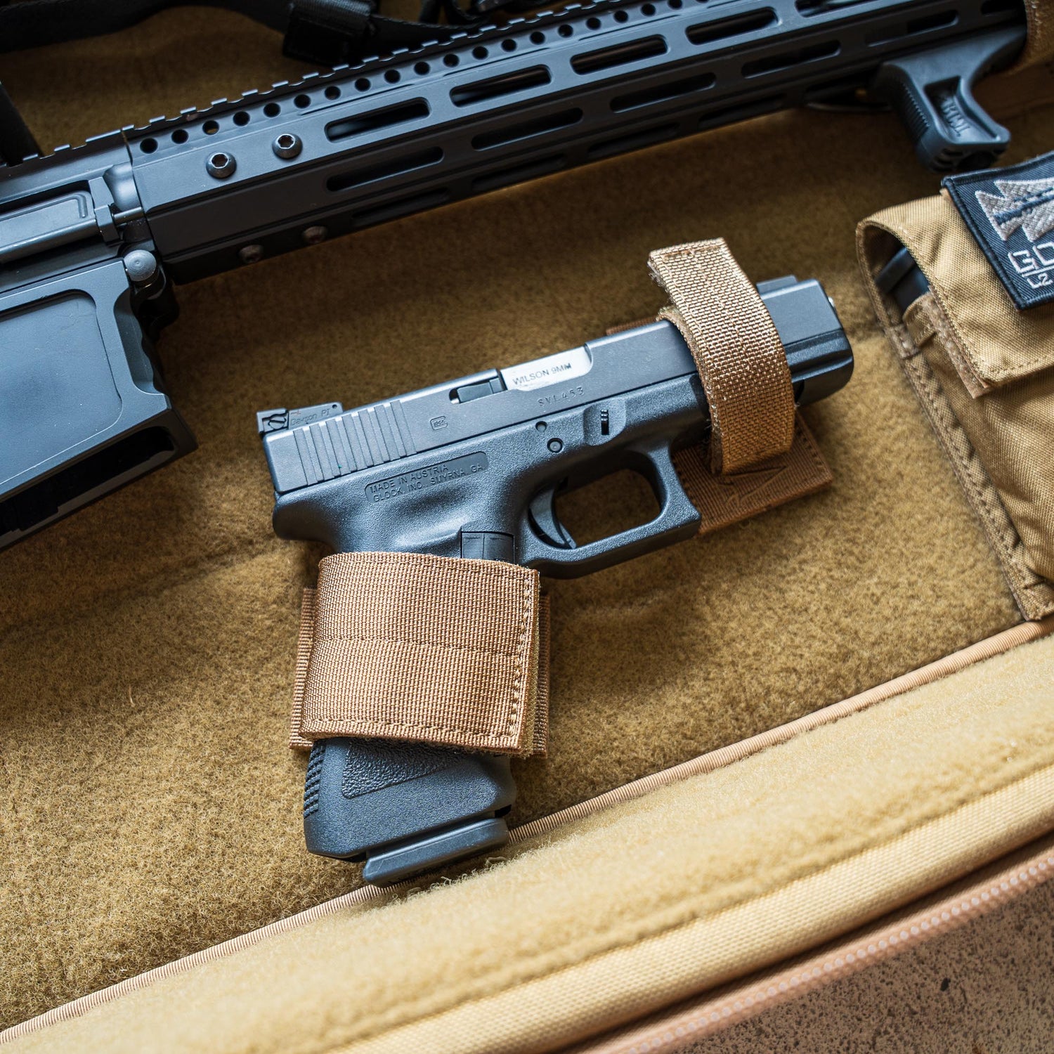A Retention Package secures a black handgun with tan straps in a padded firearm case, placed near a rifle.
