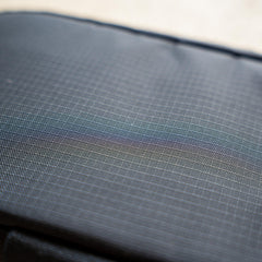 Close-up of IFAK (Black + Red Thread + Grey Interior + Red Patch) ROBIC w/ Aquaguard fabric featuring textured dark gray surface, faint grid lines, and a subtle iridescent sheen.