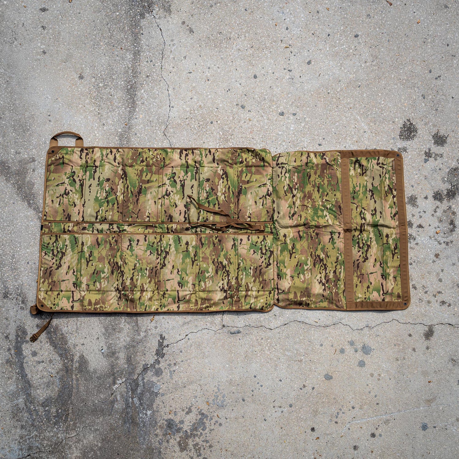 A Shooting Mat with a camouflage pattern is laid out on a concrete surface.