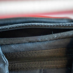 Close-up of an open, empty black Checkered GR1 21L - Built by Scars zipper pouch with visible stitching and fabric texture, highlighting the quality craftsmanship and unique designs inspired by Jax Beach, Florida.