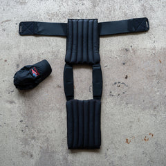 The Achilles | Men's Weighted Vest, featuring padded non-toxic construction, is laid flat on concrete beside a black baseball cap.