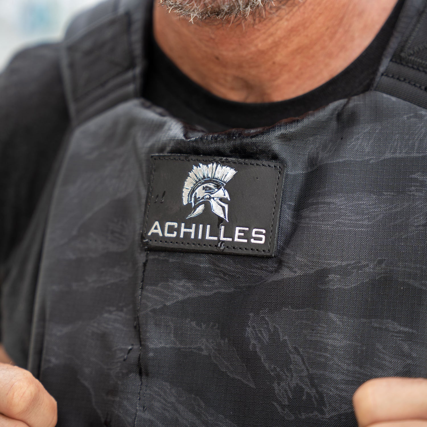Close-up of a person wearing the Achilles | Men's Weighted Vest, featuring a Spartan helmet logo patch.