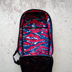 The Bullet Ruck Classic - Ballistic Nylon Cordura is open, revealing its red, blue, and white patterned lining as it lies on a concrete surface.