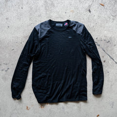 Men’s Commando Long Sleeve - Merino Wool in black, featuring reinforced shoulders and a classic commando sweater design, laid flat on a concrete surface.