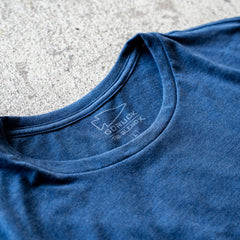 Slick Short Sleeve Tee - Tri-BlendX in blue, featuring a visible logo and label, is laid flat on a textured light surface.