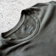 Close-up of a green collar from the Slick Short Sleeve Tee - Tri-BlendX, featuring a printed GORUCK logo and size label on the inside, highlighting the shirt's durable and comfortable premium Tri-BlendX fabric.