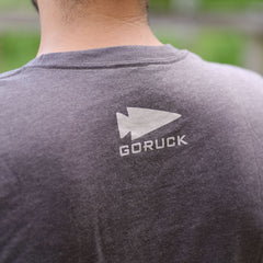Close-up of a person wearing the GORUCK Logo DCU Camo Tee - Tri-Blend, featuring the spearhead logo and arrow graphic on the back.
