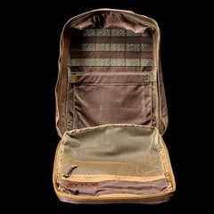 The GR1 USA - Heritage Waxed Canvas, a brown tactical pouch featuring an open zipper, mesh pocket, and multiple internal compartments, is displayed against a black background.