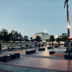 A group of people performing a rucking challenge in a public plaza at dusk.