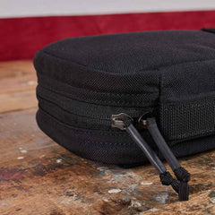 Close-up of the GR1 Field Pocket - USA, a black zippered pouch with dual zipper pulls, perfect as an electronics organizer, shown resting on a wooden surface.