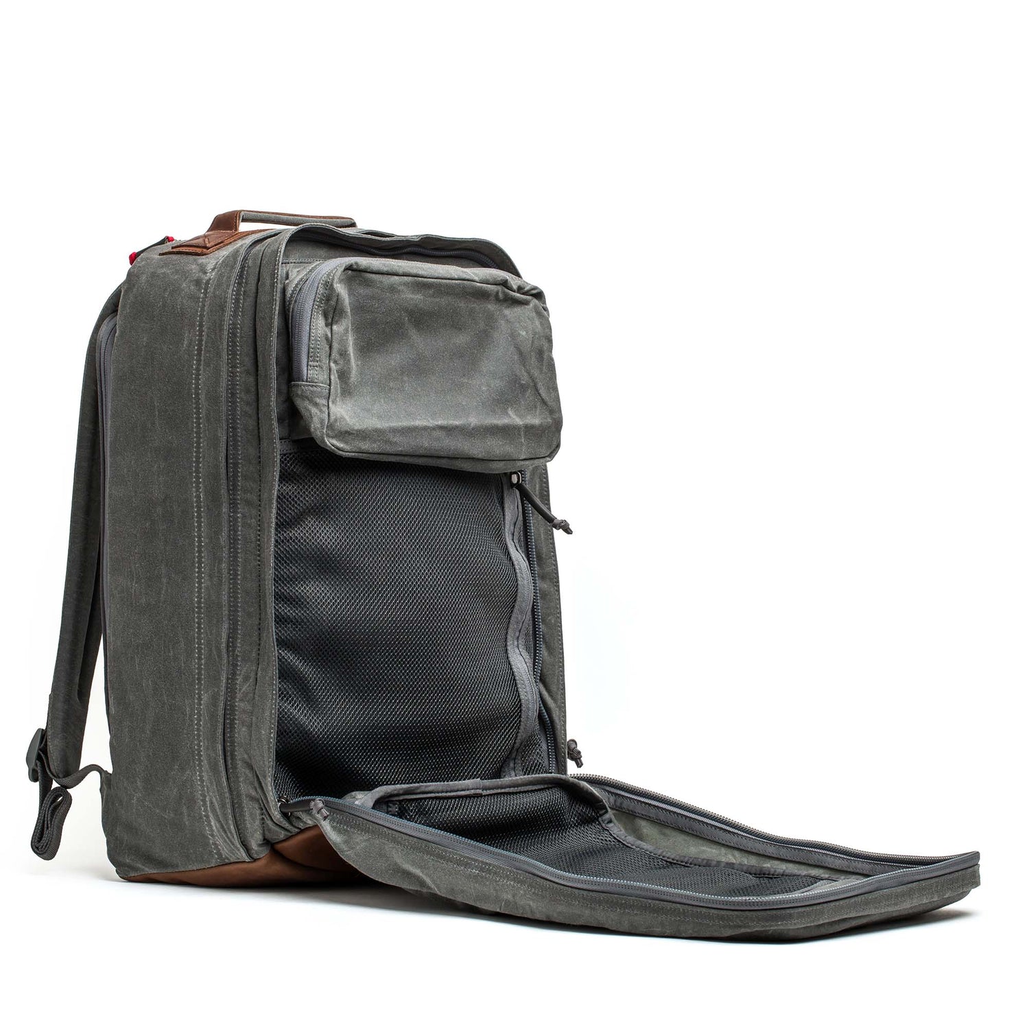 The GR2 - Heritage Waxed Canvas is a gray backpack with brown Red Wing Leather accents, shown open to highlight its interior compartments and mesh pockets—ideal as a stylish travel ruck for any journey.