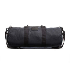 The Gym Bag - Waxed Canvas features classic black waxed canvas, two handles, a shoulder strap, and a minimalist design, all set against a white background.