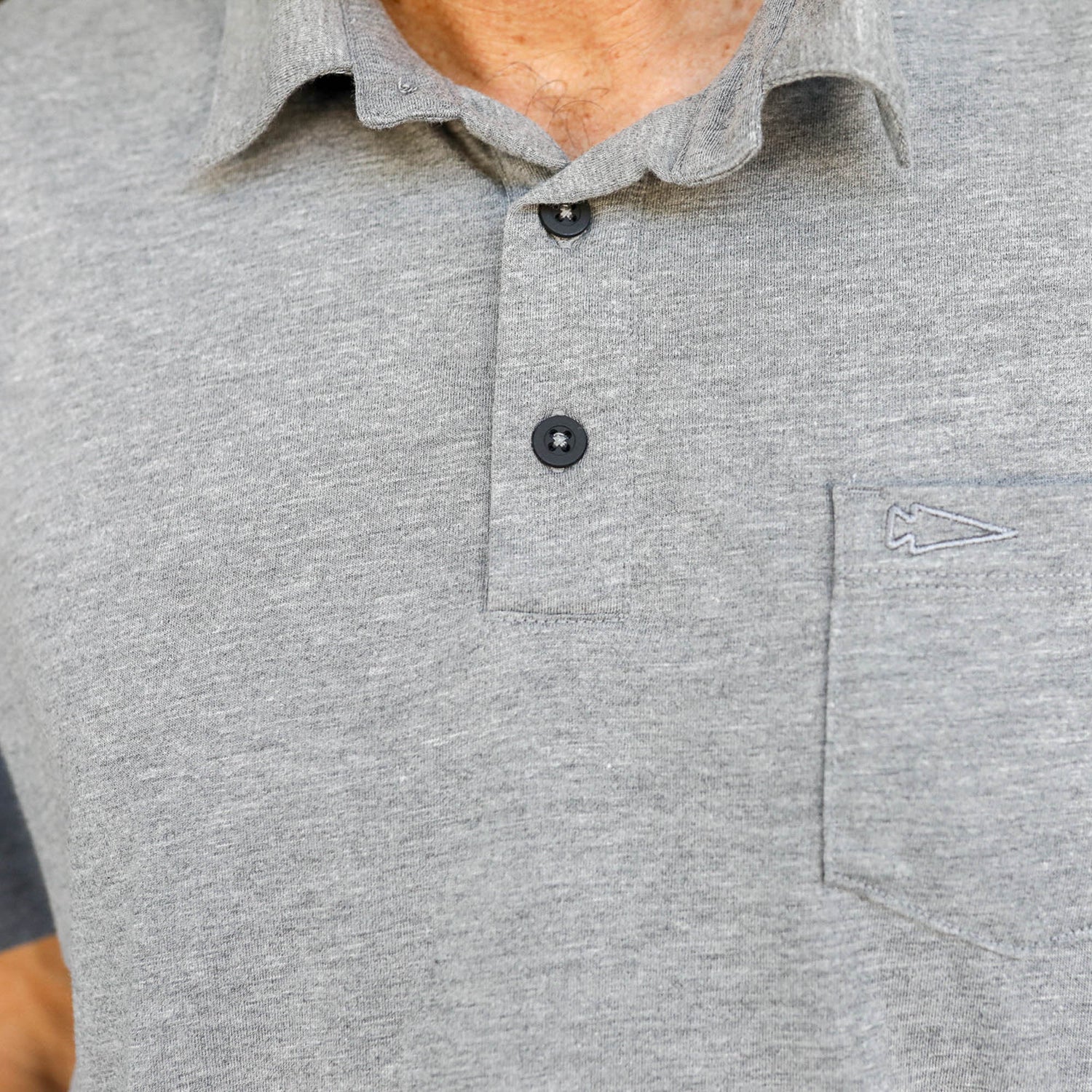 Close-up of the Men's Polo with Pocket - Tri-BlendX in gray, featuring two buttons, a left chest pocket, and crafted from premium tri-blend fabric for superior comfort.