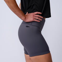 A person stands sideways with one hand on their hip, wearing a black shirt and the Women’s Biker Shorts - ToughFlex against a plain background.