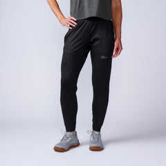 A person wears Women’s Performance Joggers made from premium performance fabric, paired with gray sneakers and a dark gray shirt, standing against a light background. Backed by the Scars Lifetime Guarantee for lasting quality.