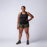 Woman in GORUCK rucking gear, black tank top, camo shorts, and athletic shoes, studio background
