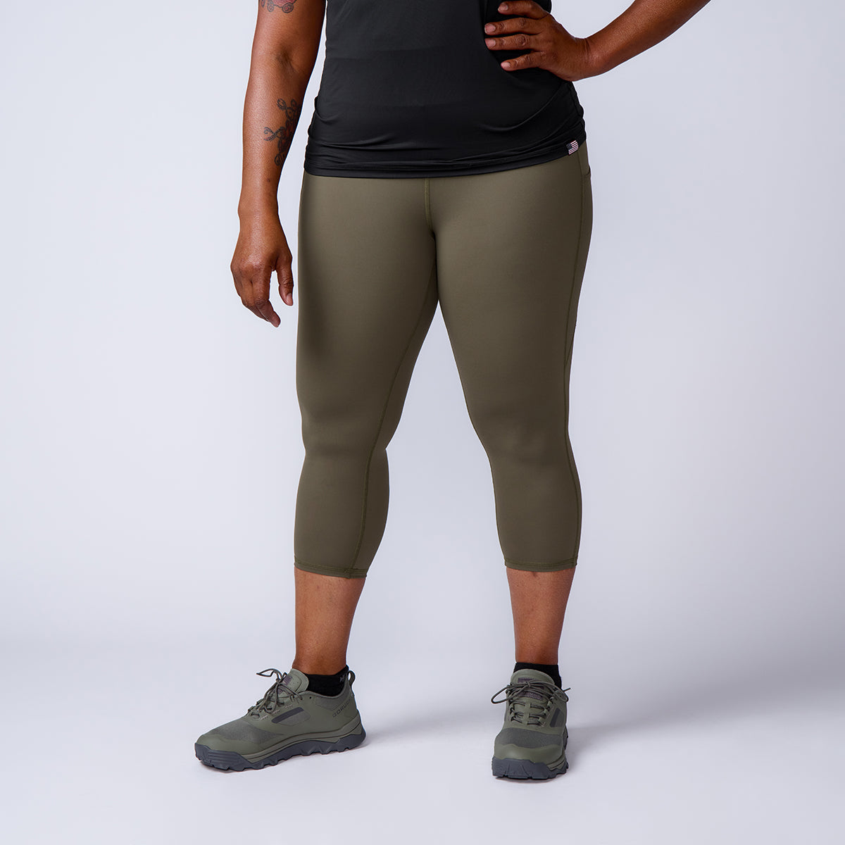 Person wearing olive green Women’s Training Leggings Pocket - ToughFlex, black shirt, and green sneakers stands against a plain light background.