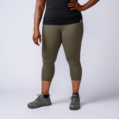 Person wearing olive green Women’s Training Leggings Pocket - ToughFlex, black shirt, and green sneakers stands against a plain light background.