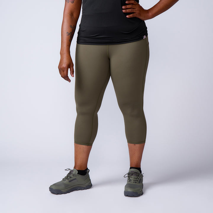 Person wearing olive green Women’s Training Leggings Pocket - ToughFlex, black shirt, and green sneakers stands against a plain light background.