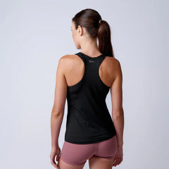 Woman wearing black racerback tank top and mauve athletic shorts standing against plain background