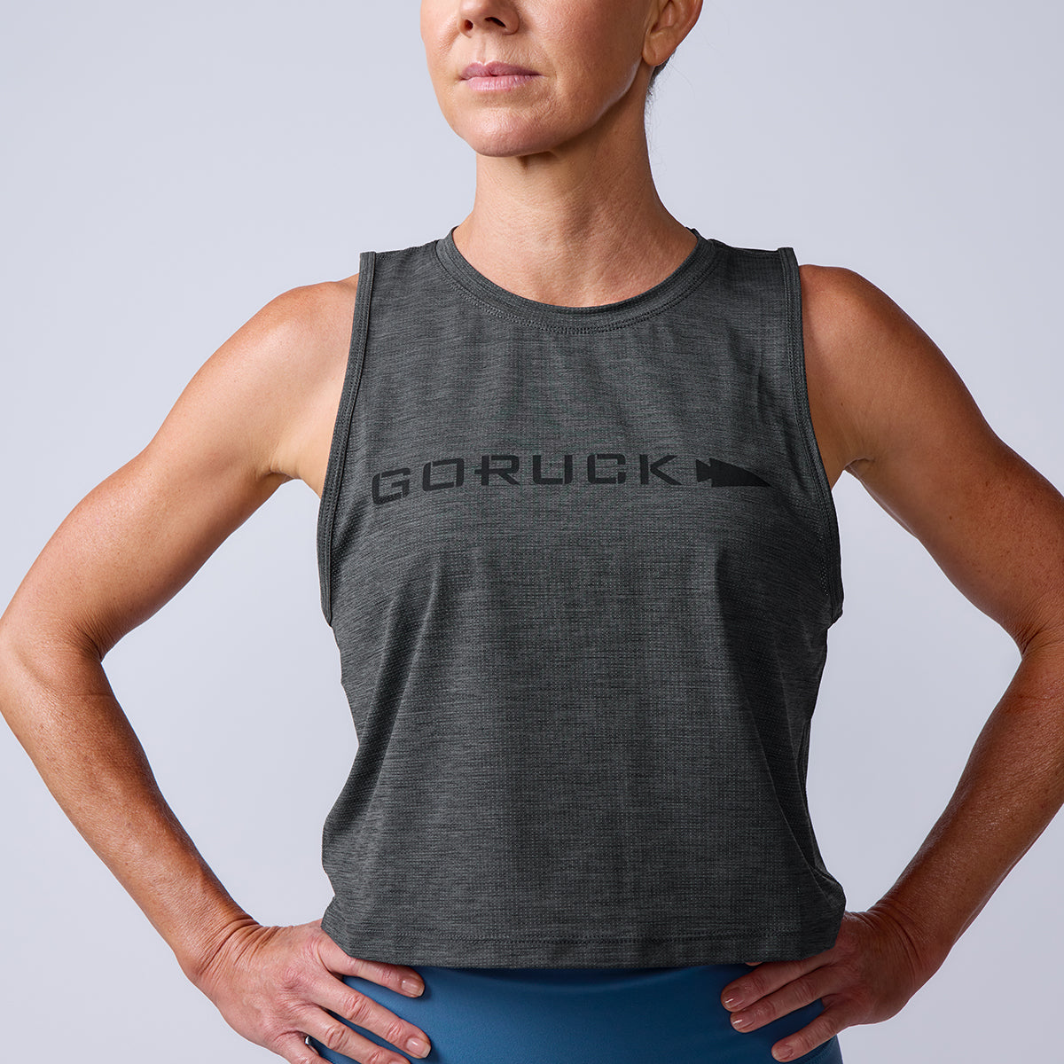 Woman wearing the Women’s USA Performance Tank - ToughMesh in gray, featuring a sleeveless design and featherweight fabric, standing with hands on hips against a plain background.
