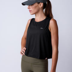 Woman wearing the Women’s USA Performance Tank - ToughMesh in black, paired with olive leggings and a gray cap, stands with hand on hip.