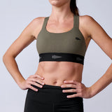 Woman wearing GORUCK olive sports bra with black arrow detail, studio background