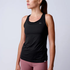 Woman wearing black athletic tank top with GORUCK logo and mauve leggings against gray background