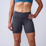 Woman wearing GORUCK black athletic shorts and teal sports bra against plain background