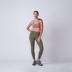 A woman in a mauve sports bra and olive green Women’s Training Leggings Pocket - ToughFlex stands against a plain light gray background.