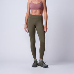 A woman wearing ToughFlex Women’s Training Leggings with pockets in olive, a mauve sports bra, and green sneakers stands against a plain background.