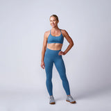 Woman in blue GORUCK athletic wear posing confidently in studio with neutral background
