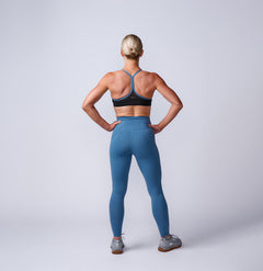 Woman in Women’s Training Leggings Pocket - ToughFlex and a sports bra stands with hands on hips, facing away—showcasing durable leggings designed for any workout.