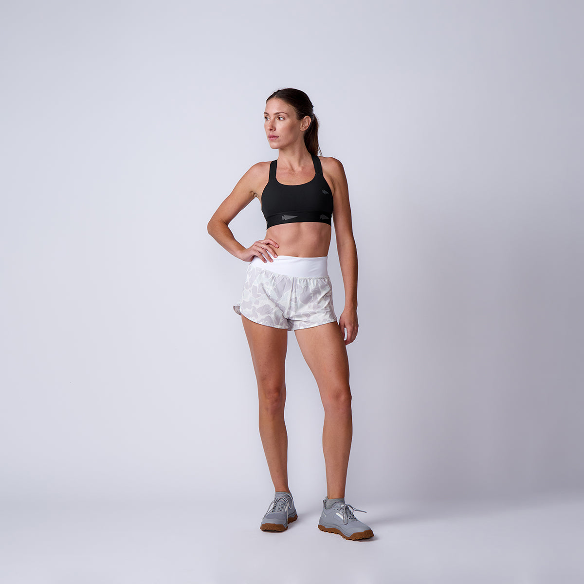 Woman in athletic wear poses against a plain background, wearing a black sports bra and Women’s Training Shorts - ToughStretch, designed for ultimate comfort.