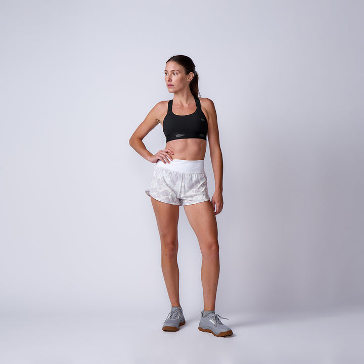 Woman in athletic wear poses against a plain background, wearing a black sports bra and Women’s Training Shorts - ToughStretch, designed for ultimate comfort.