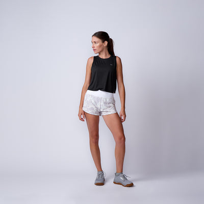Woman in a black tank top, Women’s Training Shorts - ToughStretch, and gray sneakers stands against a plain light background.
