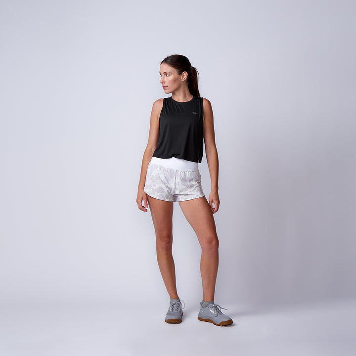 Woman in a black tank top, Women’s Training Shorts - ToughStretch, and gray sneakers stands against a plain light background.