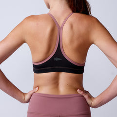 Woman in mauve ToughFlex Stealth Bra, back to camera with hands on hips, showcasing this minimalist sports bra designed for lightweight support.