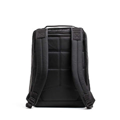 Back view of a black GORUCK rucksack with padded shoulder straps and a handle on white background