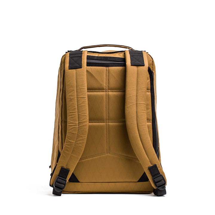 The GR0 - X-PAC is a mustard yellow lightweight rucksack made from waterproof X-PAC material, featuring padded shoulder straps and black accent details, shown from the back.