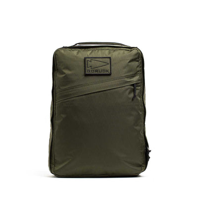 The GR0 - X-PAC is an olive green backpack made from lightweight, waterproof rucksack material, featuring a diagonal zip pocket and a rectangular "GORUCK" patch on the front.