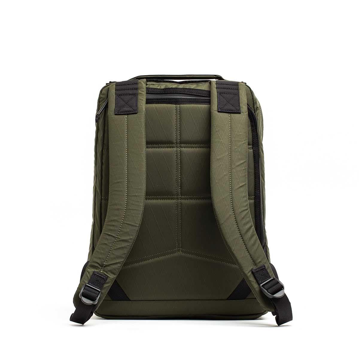 The GR0 - X-PAC backpack in olive green is shown from the back, featuring padded shoulder straps, quilted padding, and a bombproof laptop compartment.