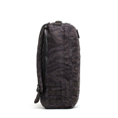 Side view of the GR1 USA - Cordura in dark camouflage, featuring multiple straps and a zipper, standing upright on a white background—an everyday carry backpack built with Special Forces grade durability.