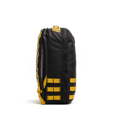The GR1 backpack in black, featuring yellow straps and accents, is pictured upright on a white background from the side.