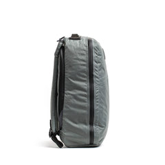 Side view of a gray durable GORUCK rucksack with black zippers on white background