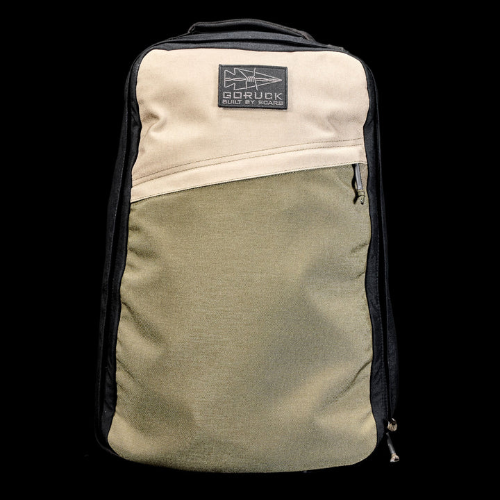 The GR1 Shooter 26L - Built by Scars is a two-tone backpack with tan and olive panels on black CORDURA®, finished with a GORUCK patch.