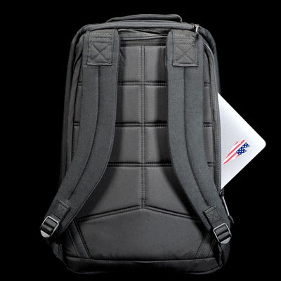 A GR1 Shooter 26L - Built by Scars backpack in gray, featuring durable CORDURA® and padded straps, holds a laptop partially visible in the back pocket against a black background.