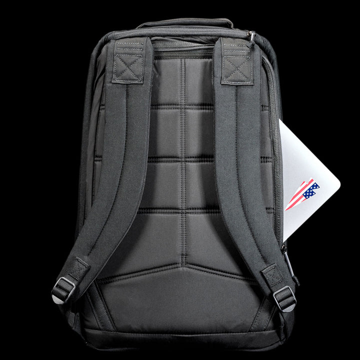 A GR1 Shooter 26L - Built by Scars backpack in gray, featuring durable CORDURA® and padded straps, holds a laptop partially visible in the back pocket against a black background.