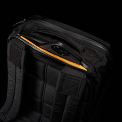 Close-up of black GORUCK rucksack showing padded back, shoulder straps, and partially open yellow-lined compartment with smartphone inside